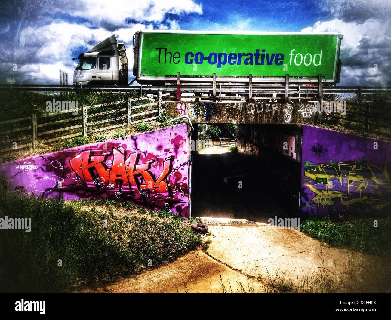 Co-op cibo camion su A1 passando sopra alla metropolitana decorato con graffiti. Eaton Socon, Cambridgeshire, Inghilterra. - Immagine stock catturata con smartphone