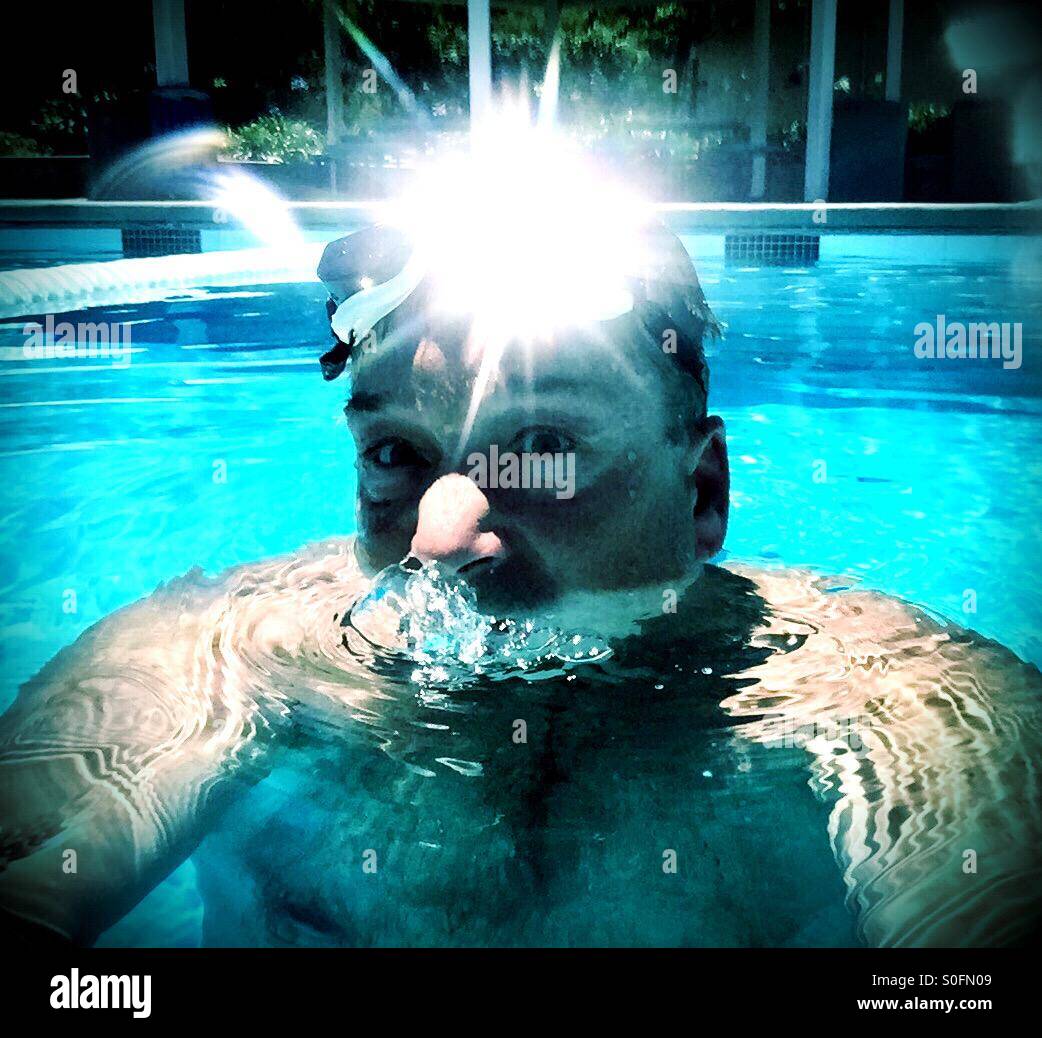 Sole brillante riflessioni dal nuotatore di occhiali da nuoto nella piscina esterna. Primo piano volto, occhiali, piscina. Foto Stock