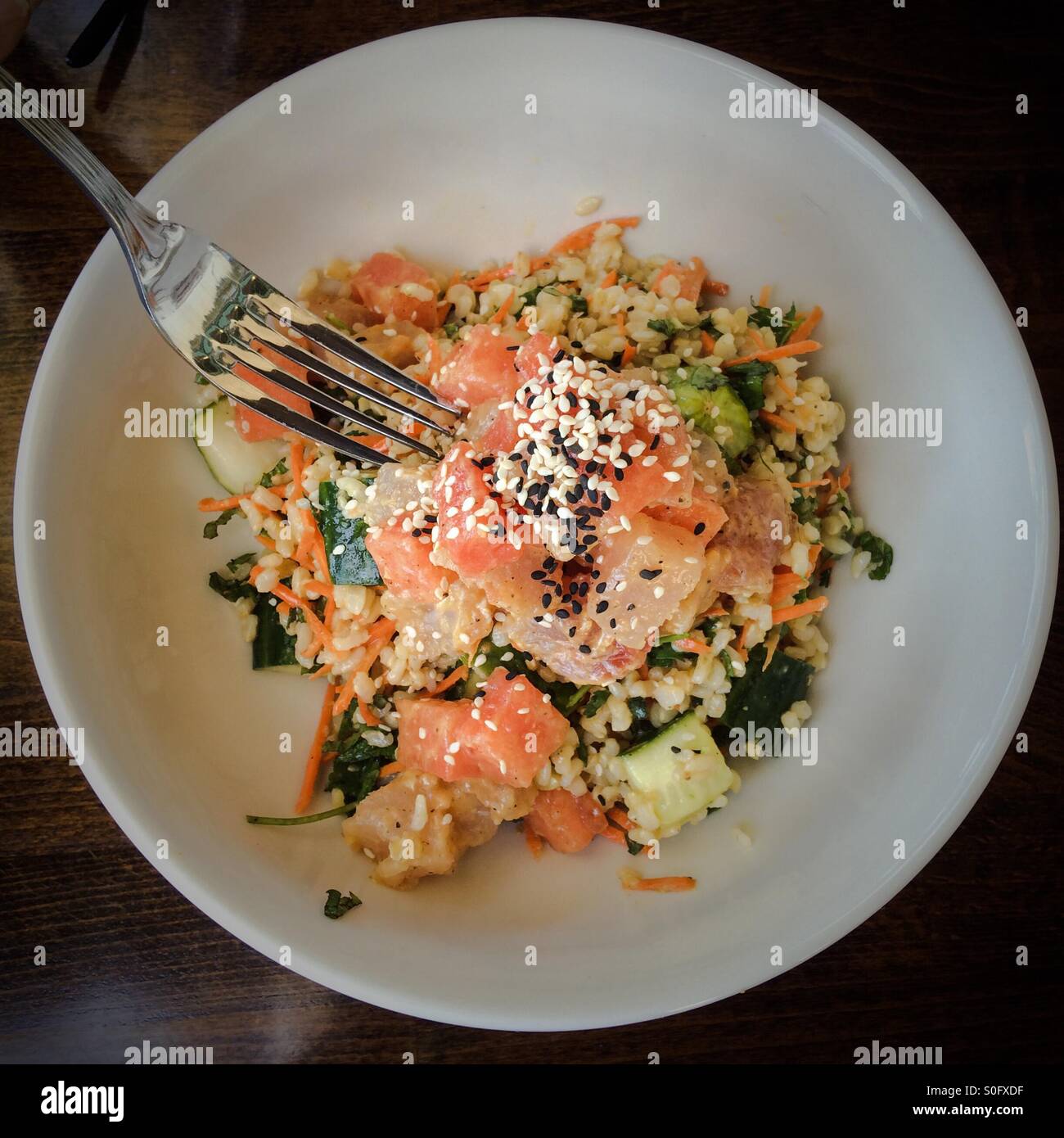 Tonno di Hawaiian poke insalatiera con cocomero, riso marrone, Carote Cetrioli e una noce di cocco-mango condimento per insalata - Immagine stock catturata con smartphone