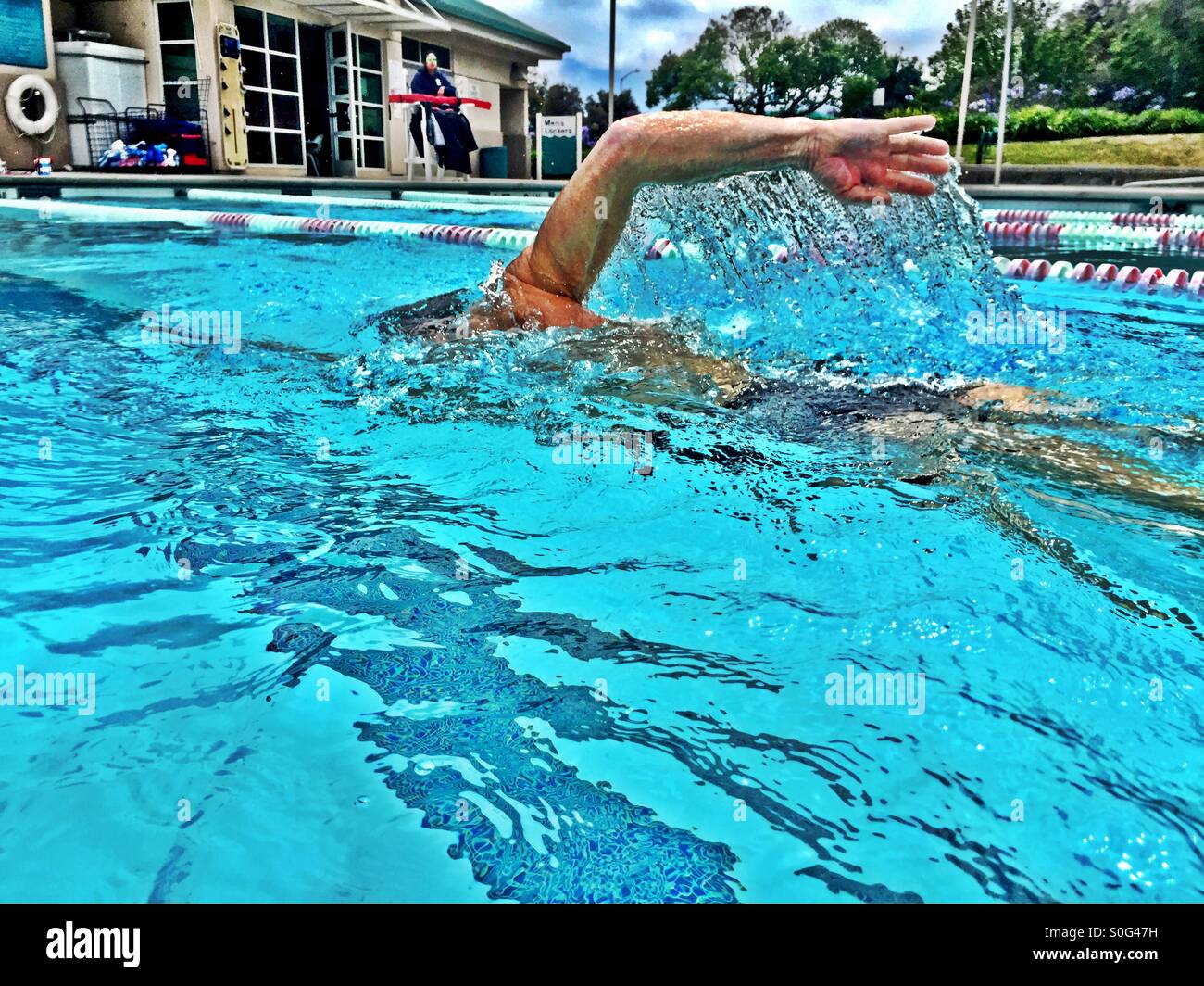 Il nuotatore. Primo piano vista dalla corsia adiacente, atleta nuoto freestyle crawl australiano a Swim Meet. HDR. Foto Stock