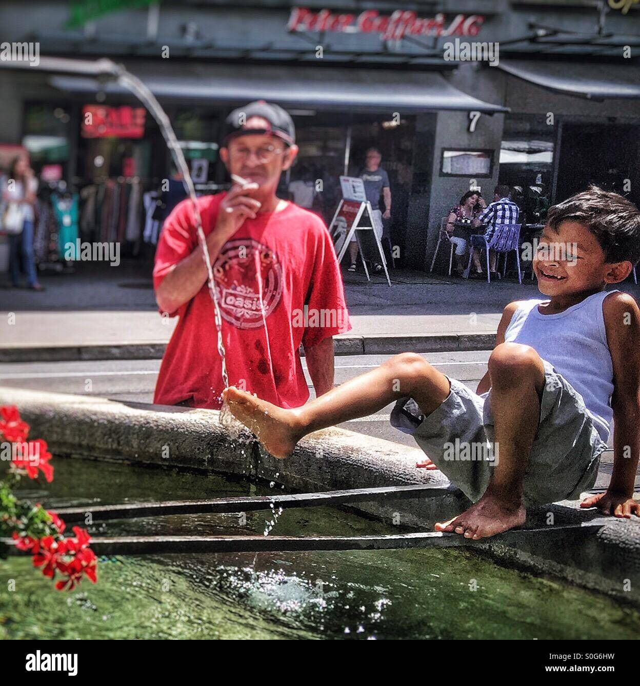 Canicola Europa- boy non si raffredda in una fontana medievale di Berna, Svizzera - Immagine stock catturata con smartphone