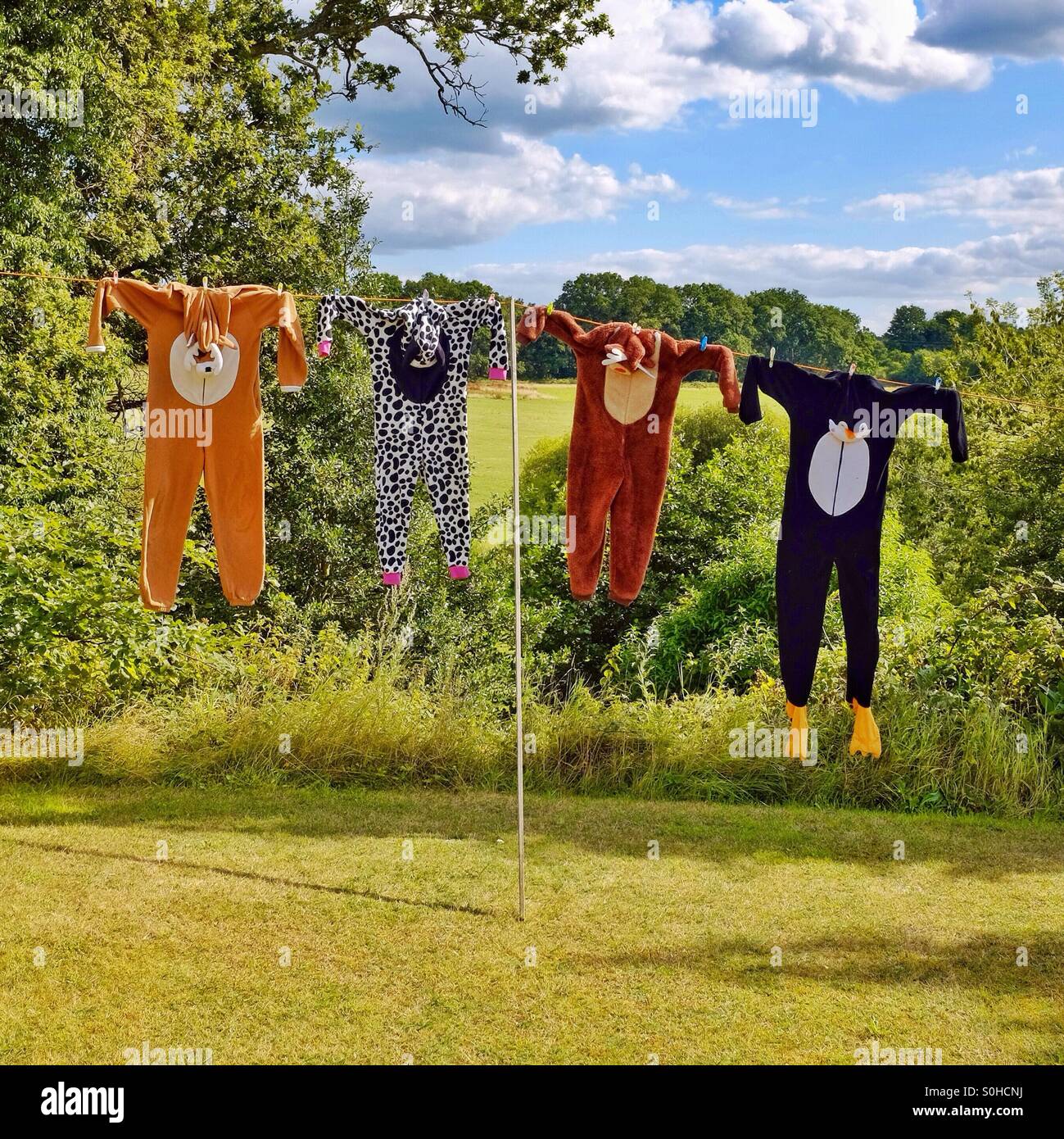 La famiglia onesie - lavato onesies animale essiccazione su la linea di abbigliamento che assomigliano a animale cacciato trofei della pelle Foto Stock