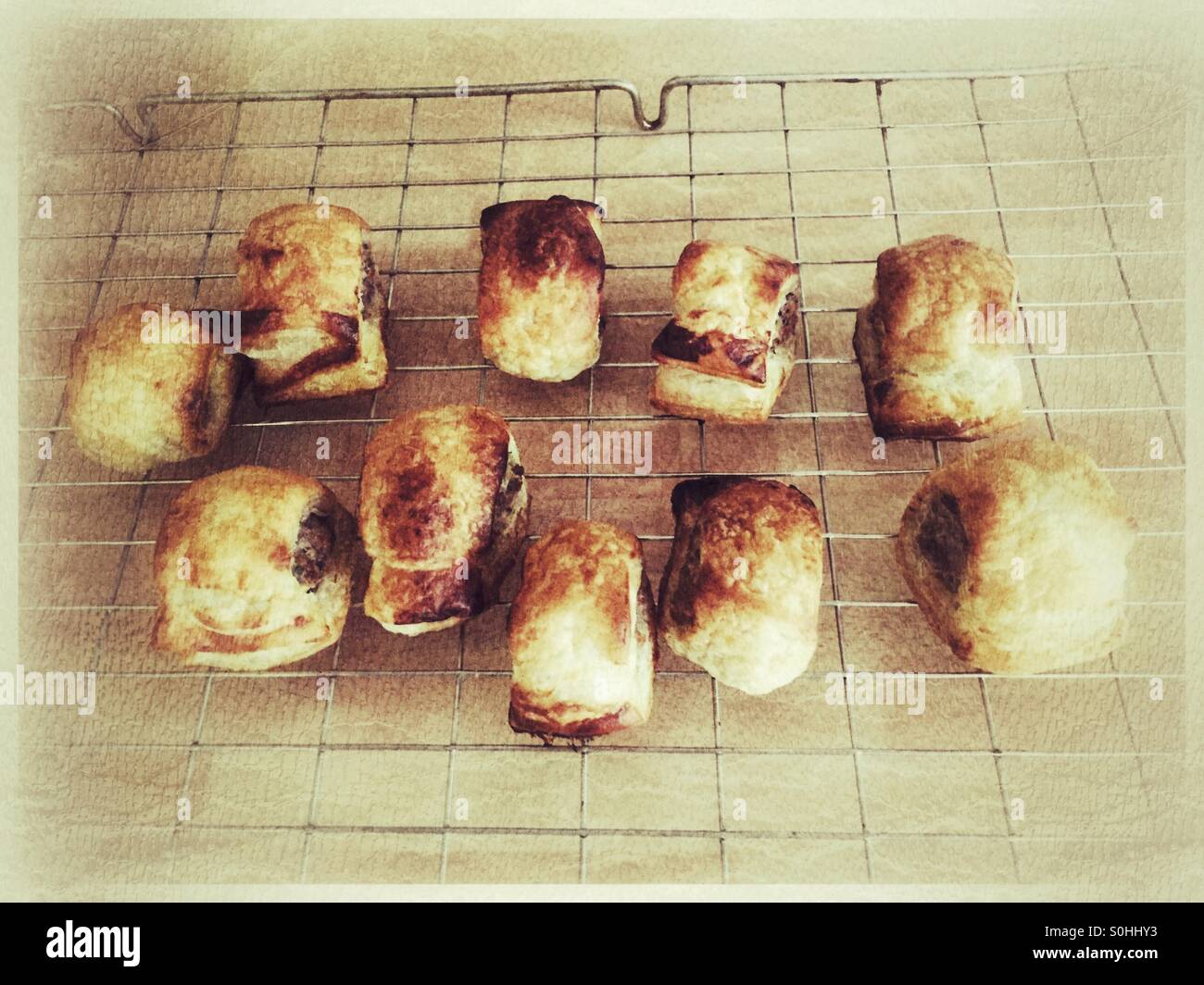 Freschi di forno rotoli di salsiccia raffreddare su una griglia con filtro grunge. Foto Stock