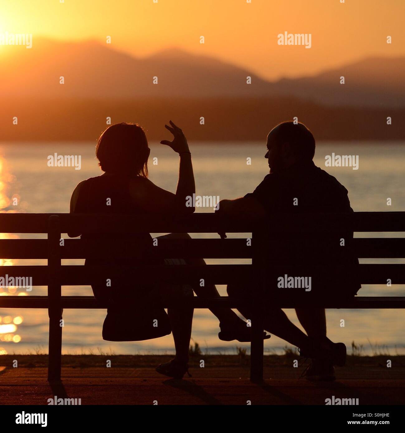 Intensa conversazione, tramonto sulla spiaggia di Alki, Seattle, Washington, una panchina nel parco Foto Stock