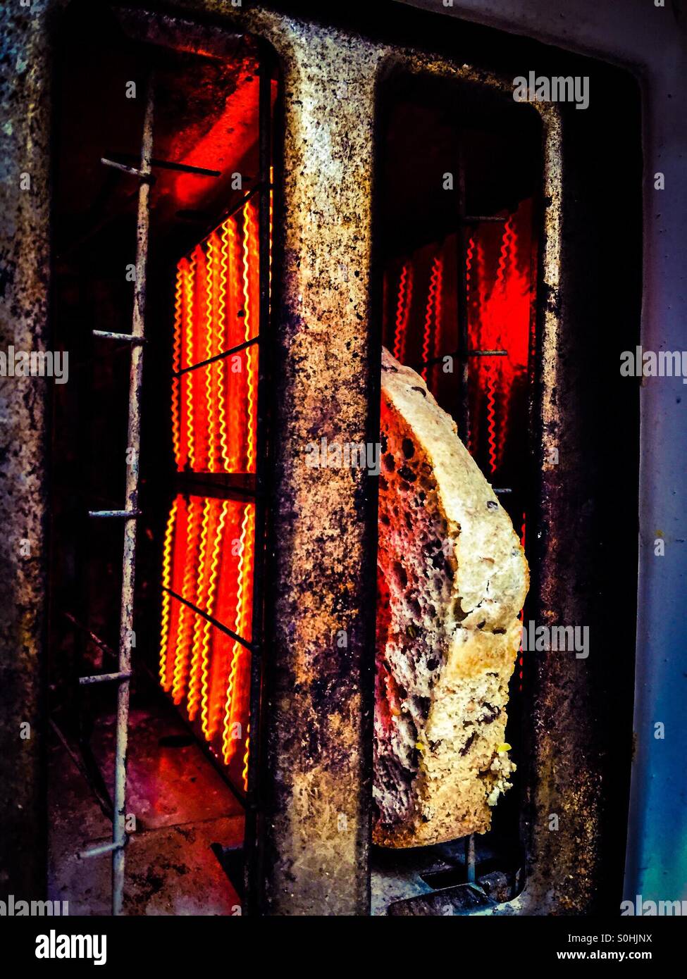 Tostapane caldo, una fetta singola di pane schioccato. Un pezzo di pane tostato quasi pronto. Elemento caldo rosso. Molto usato. - Immagine stock catturata con smartphone