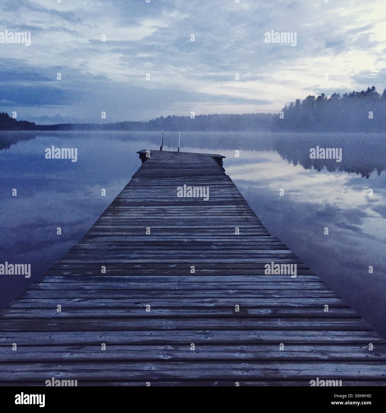 Un molo in legno su misty estate finlandese notte Foto Stock