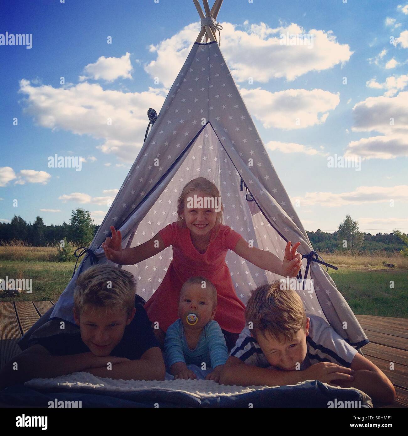 Quattro fratelli insieme in teepee su caldo giorno d'estate Foto Stock