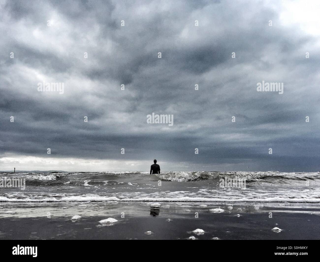 L'uomo del ferro si affaccia al mare a Crosby Beach. Antony Gormley è un altro luogo sculture Foto Stock