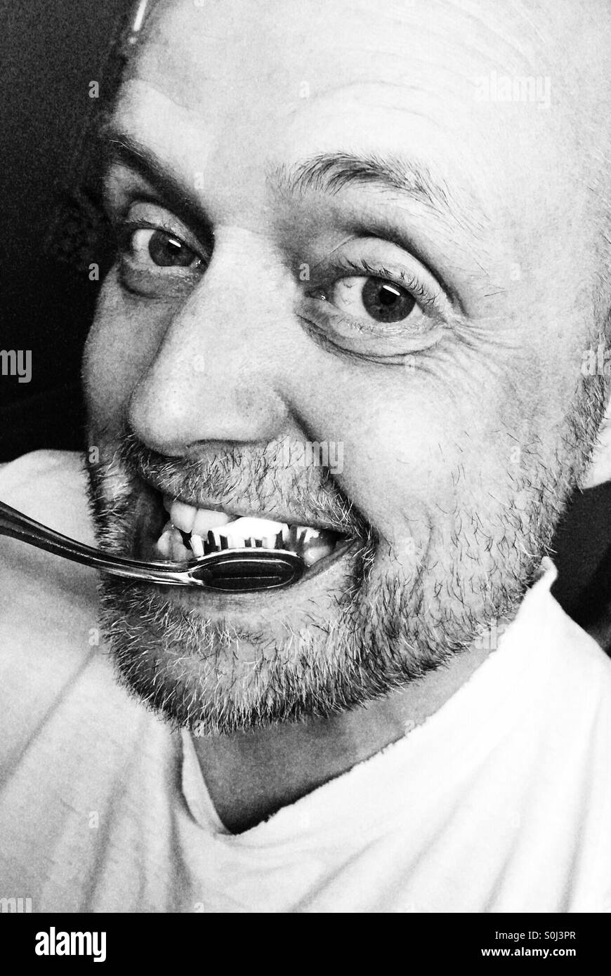 Uomo di 50 anni spazzolando i suoi denti Foto Stock