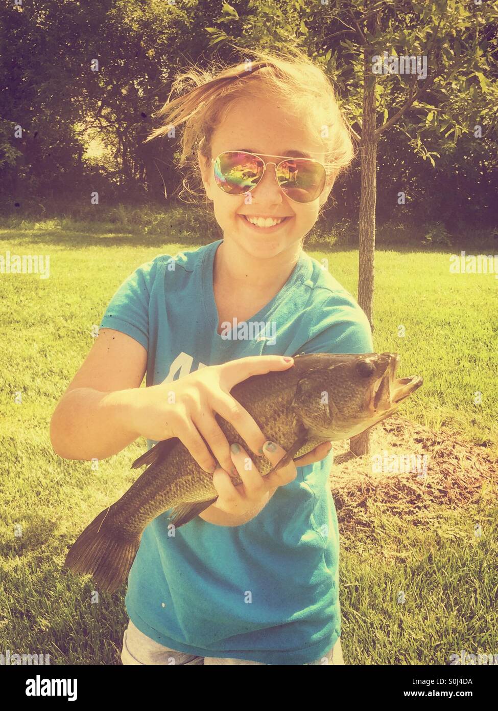 Giovane ragazza tenendo un Largemouth Bass ha catturati durante la pesca Foto Stock
