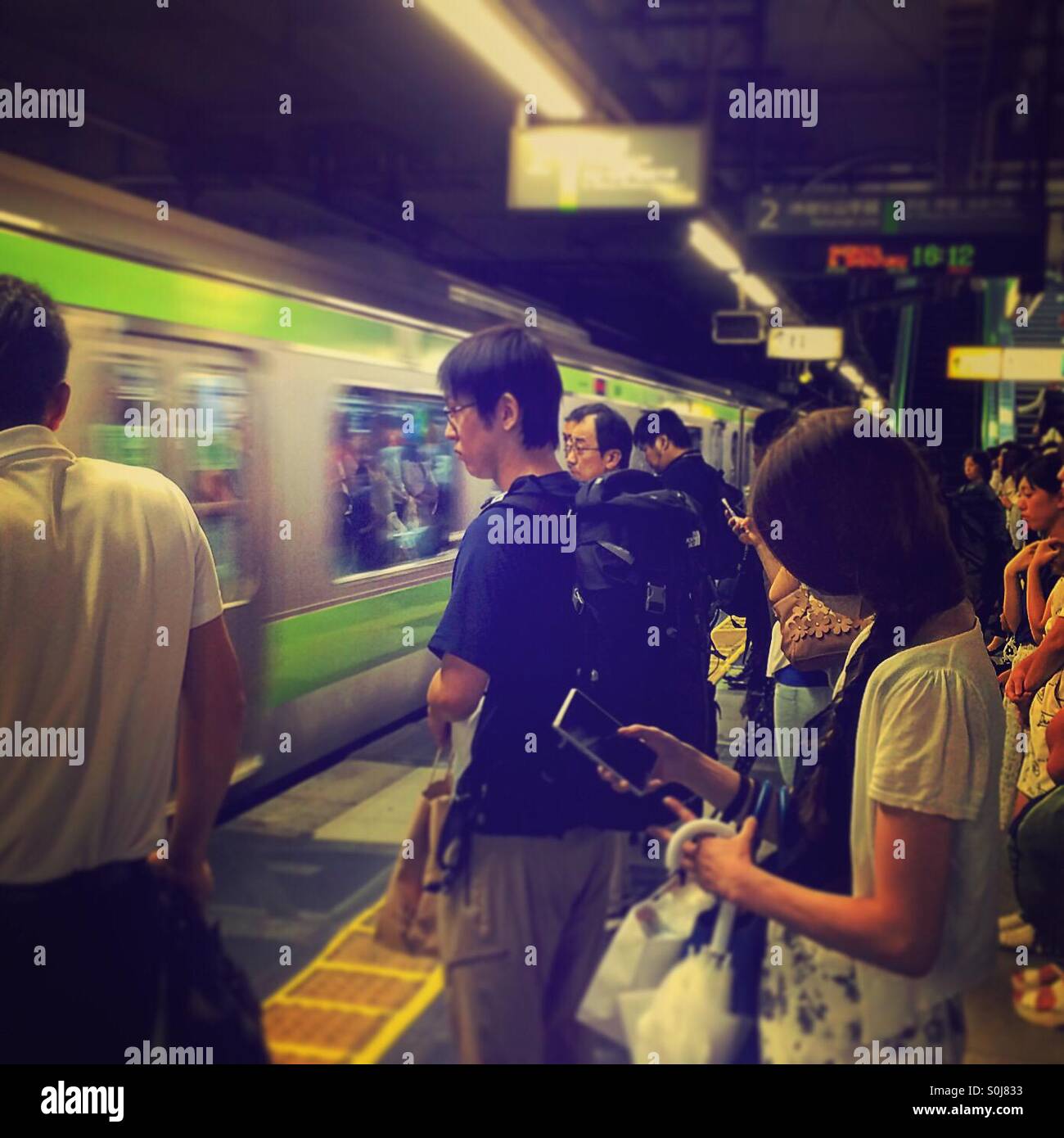 Il pendolarismo passeggeri in piedi su una piattaforma sulla metropolitana di Tokyo Linea Yamanote Foto Stock