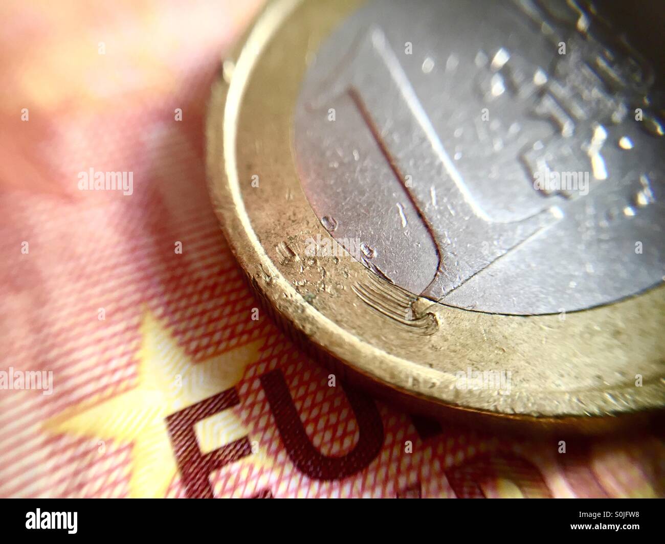 Close up di un graffiato 1€ euro moneta oltre a 10€ banconota - Immagine stock catturata con smartphone