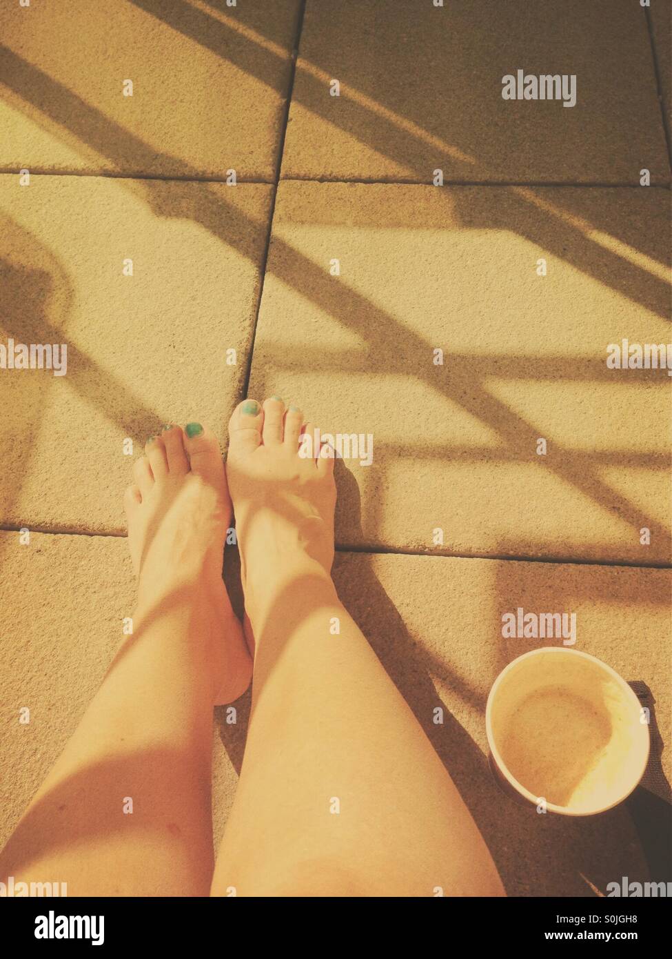 Bere il caffè al sole, con gambe nude e ombre Foto Stock