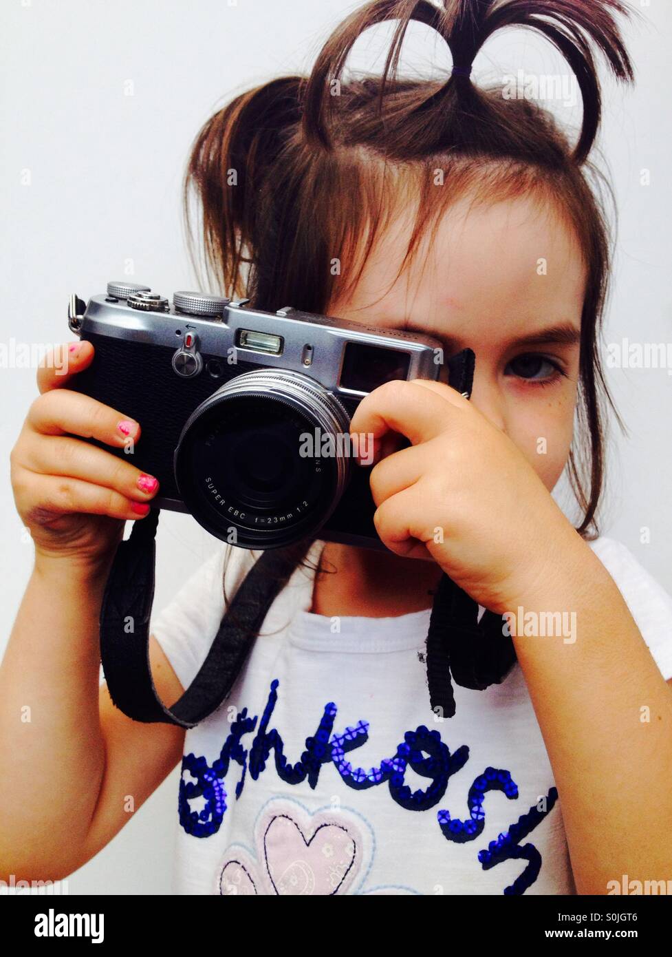 3 anno vecchia ragazza guarda attraverso il mirino della fotocamera Foto Stock