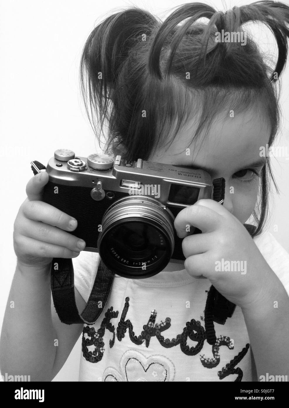 3 anno vecchia ragazza guarda attraverso il mirino della fotocamera Foto Stock