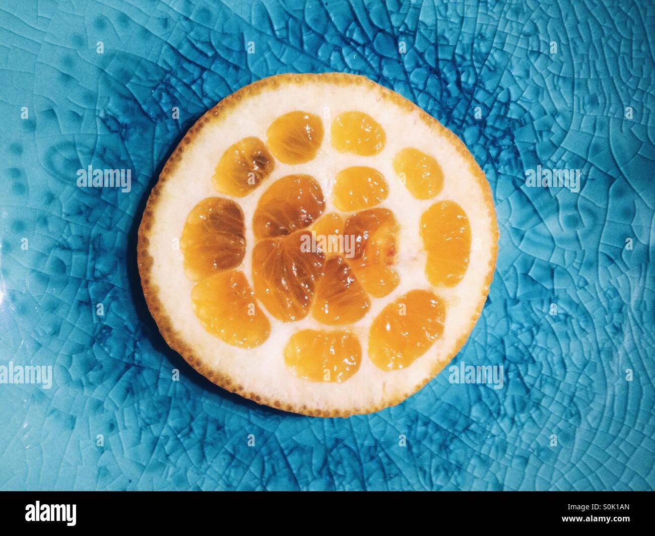 Fetta di arancio su una piastra di colore blu Foto Stock