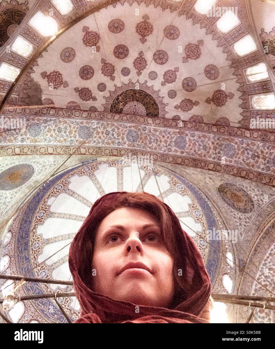 Selfie della donna in una sciarpa all'interno della Moschea Blu vista al soffitto con splendide arcate, Istanbul, Turchia Foto Stock