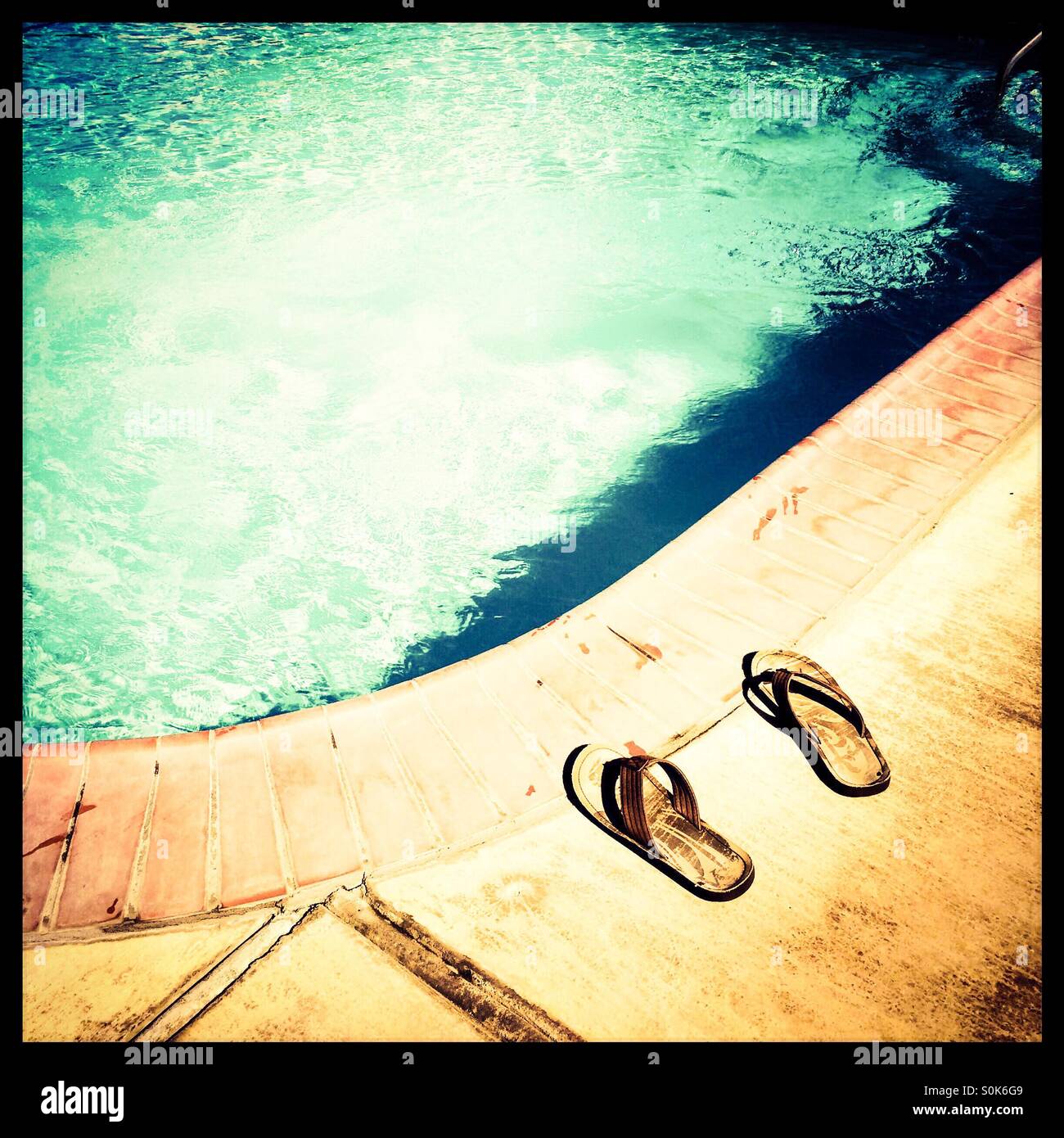 Un paio di sandali in corrispondenza di un bordo di una piscina. - Immagine stock catturata con smartphone