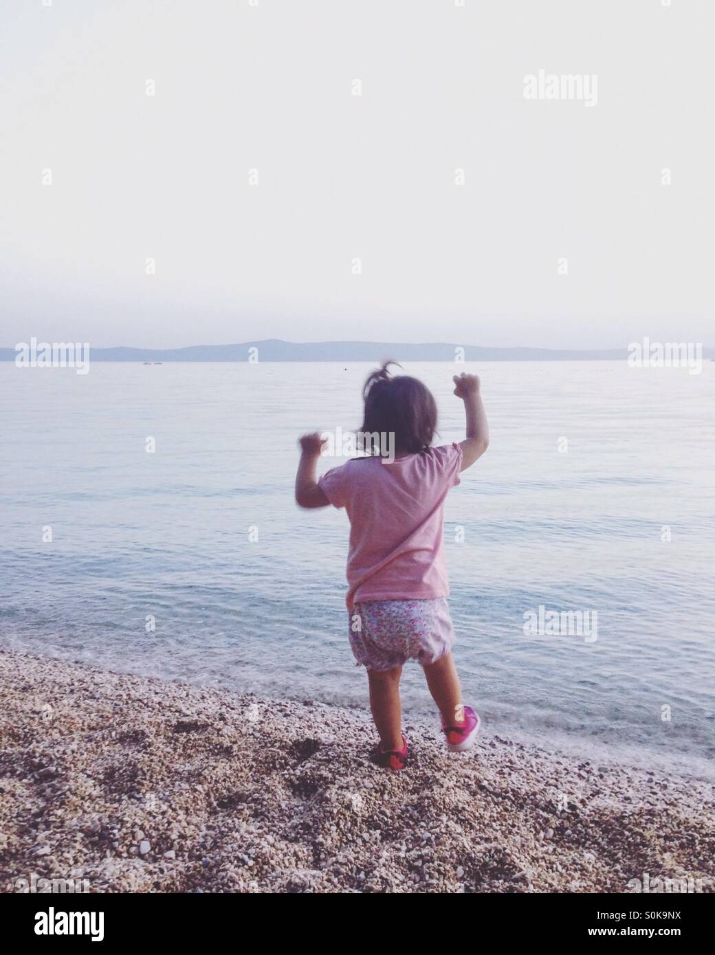 Piccola bambina sulla spiaggia vicino il mare calmo Foto Stock