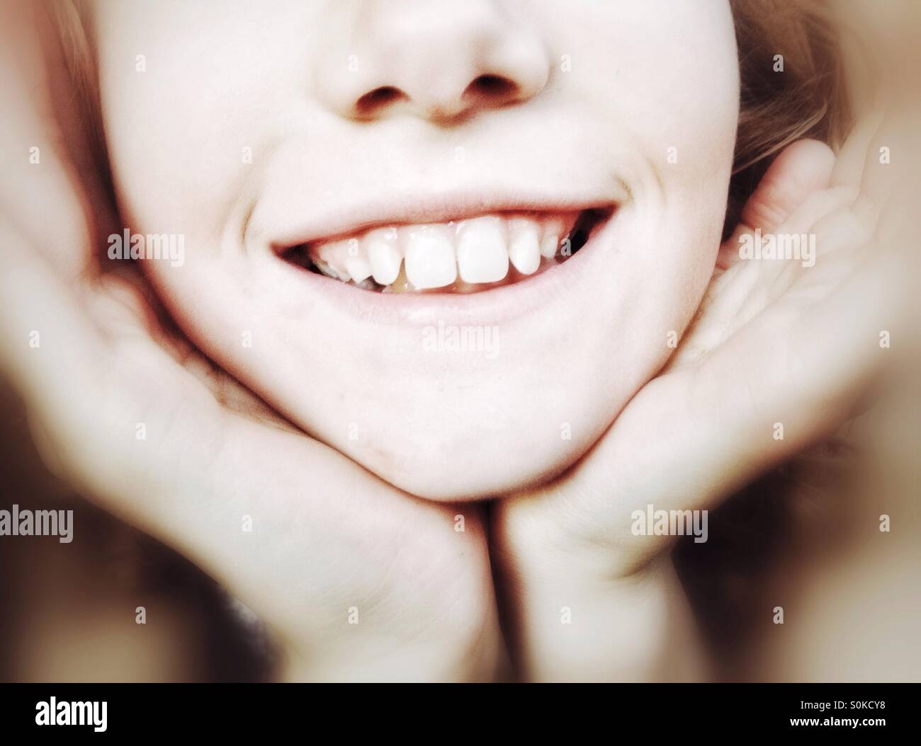 La faccia inferiore della ragazza sorridente con il suo mento tazza nelle sue mani Foto Stock