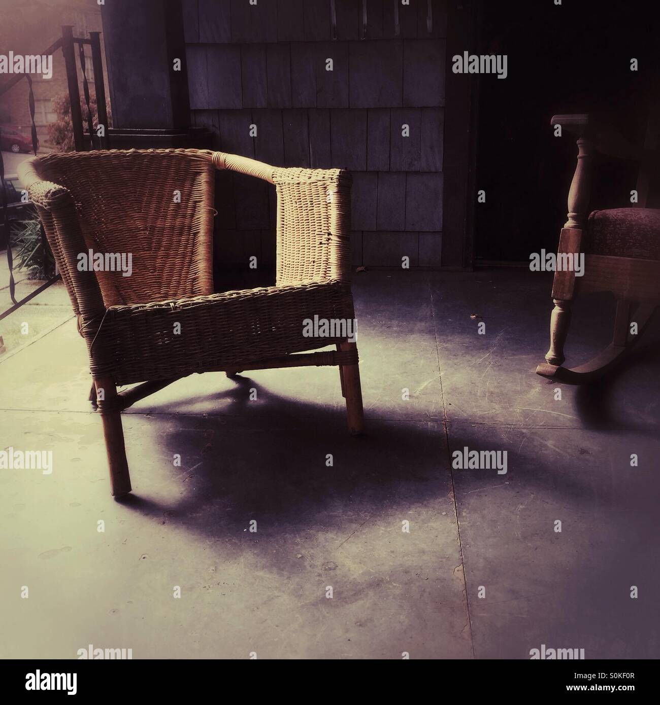 Una vecchia sedia di vimini in veranda Foto Stock
