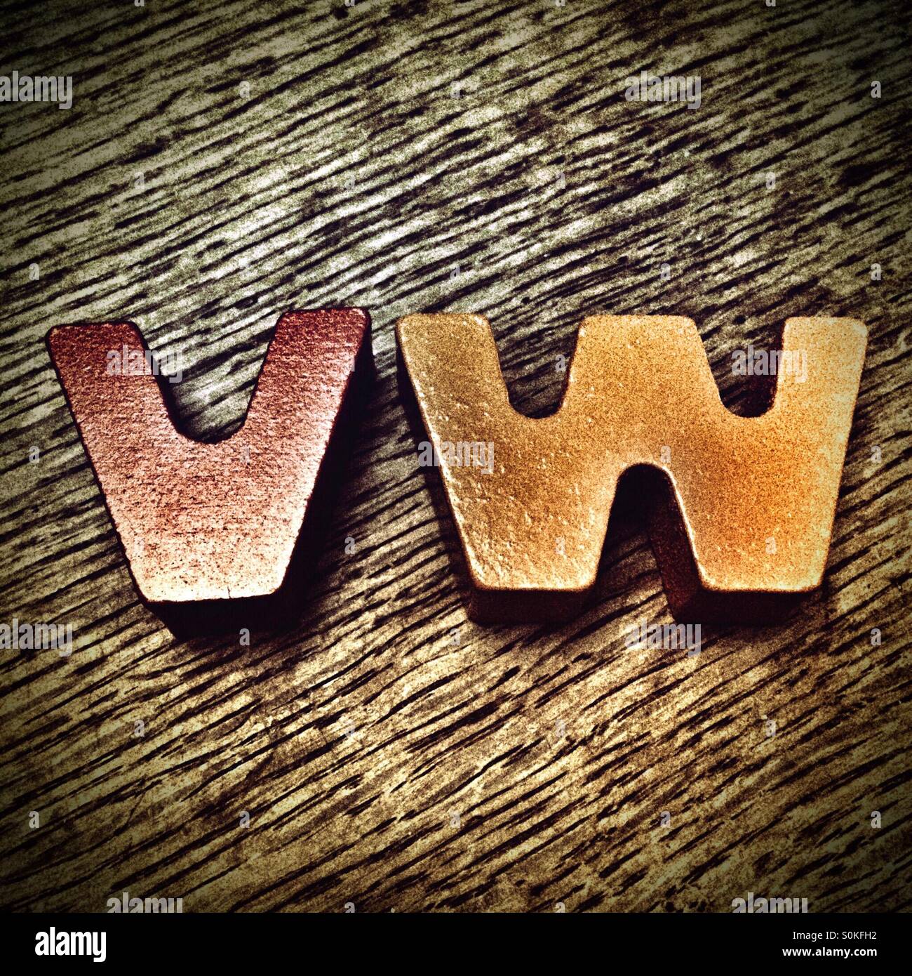 Le lettere V W fatta di giochi per bambini mattoni su uno sfondo di legno Foto Stock