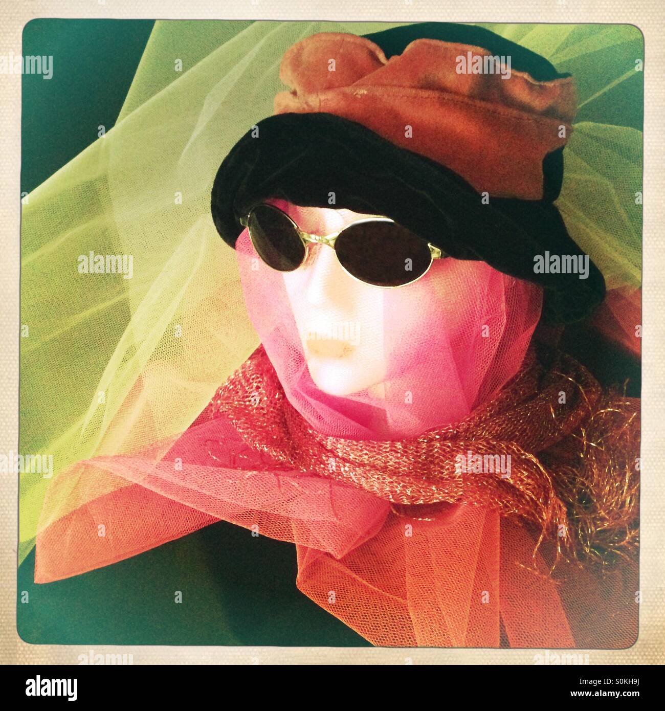 Manichino della signora della testa con hat,occhiali da sole,sciarpa, coperte in rosa e bianco netting Foto Stock