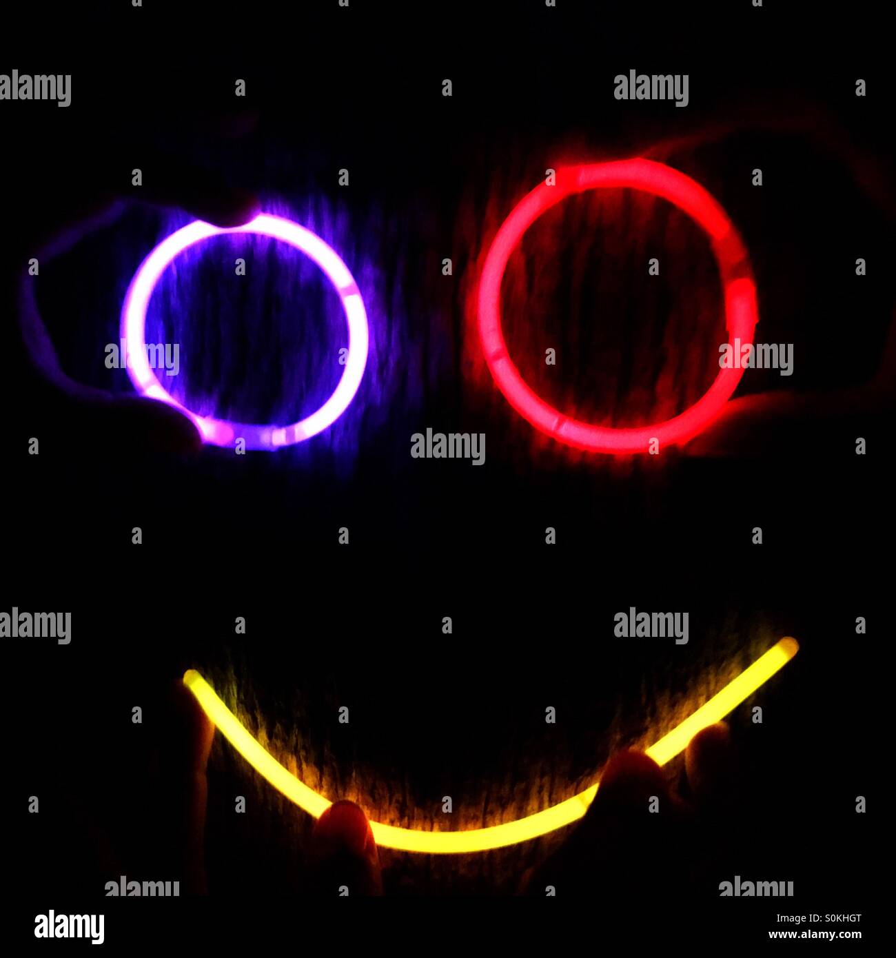 La realizzazione di una faccia su un albero di notte fatta di bastoni di incandescenza Foto Stock