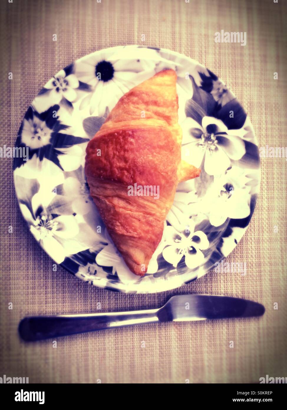 Croissant su una piastra con un coltello. Vintage guardare film. - Immagine stock catturata con smartphone