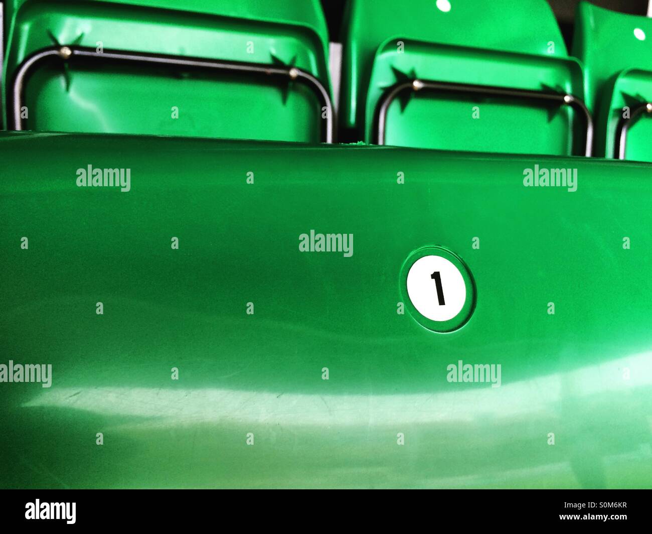 Il numero uno su una piegatura sedia verde in tribuna a uno stadio sportivo. Foto Stock
