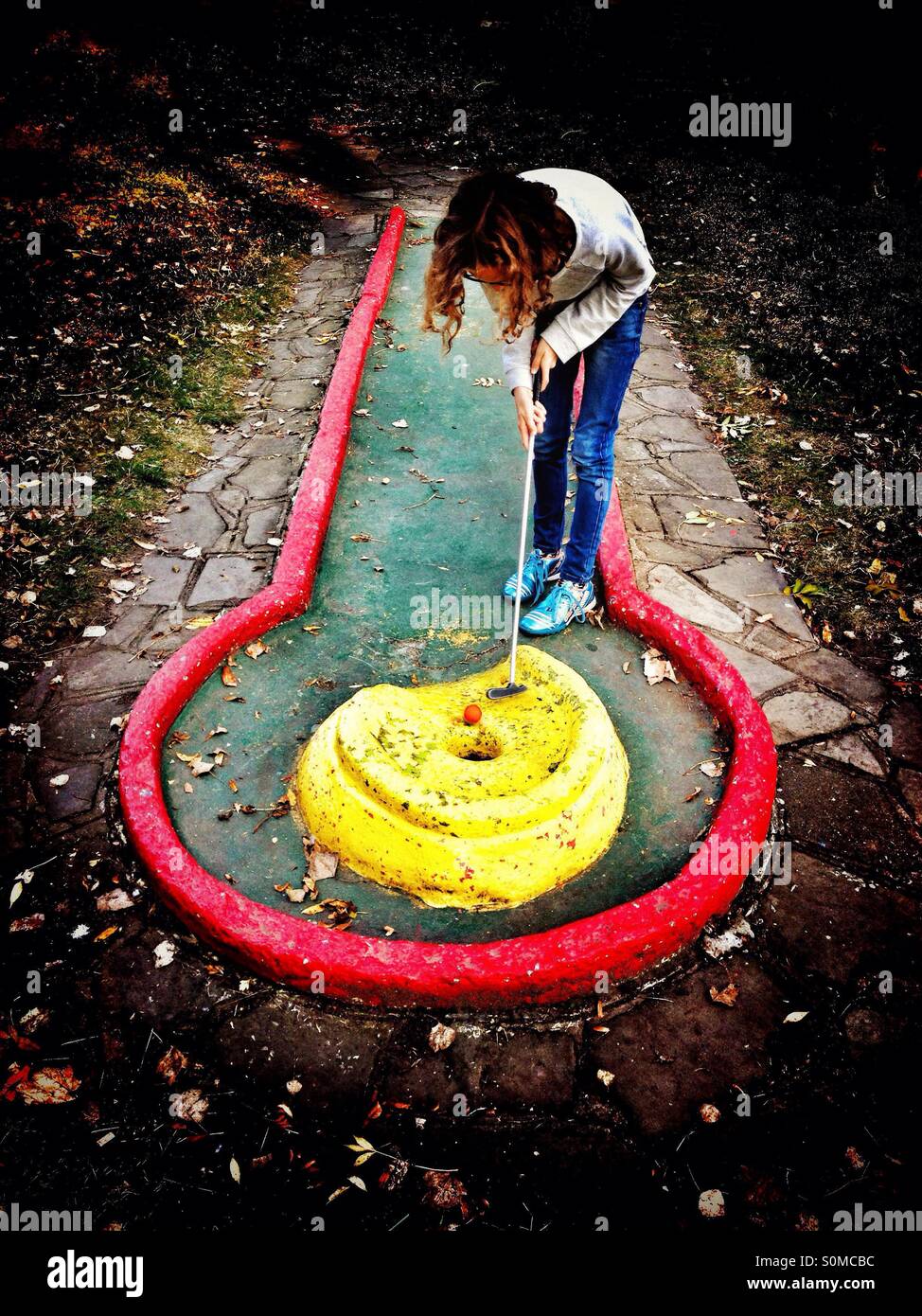 Ragazza giovane a giocare a minigolf Foto Stock