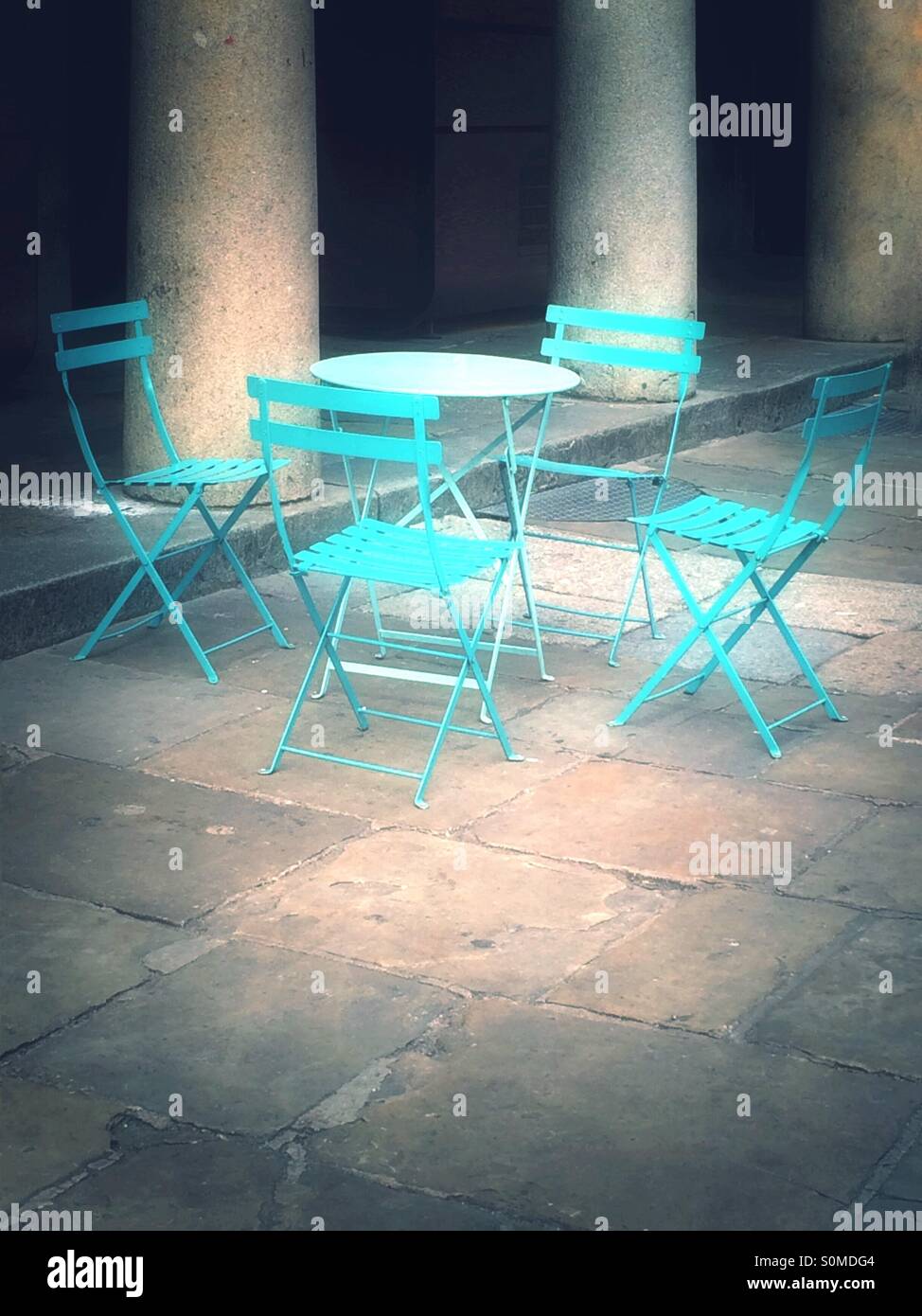 Quattro colorate sedie blu e una tabella in un ambiente da giardino. Foto Stock