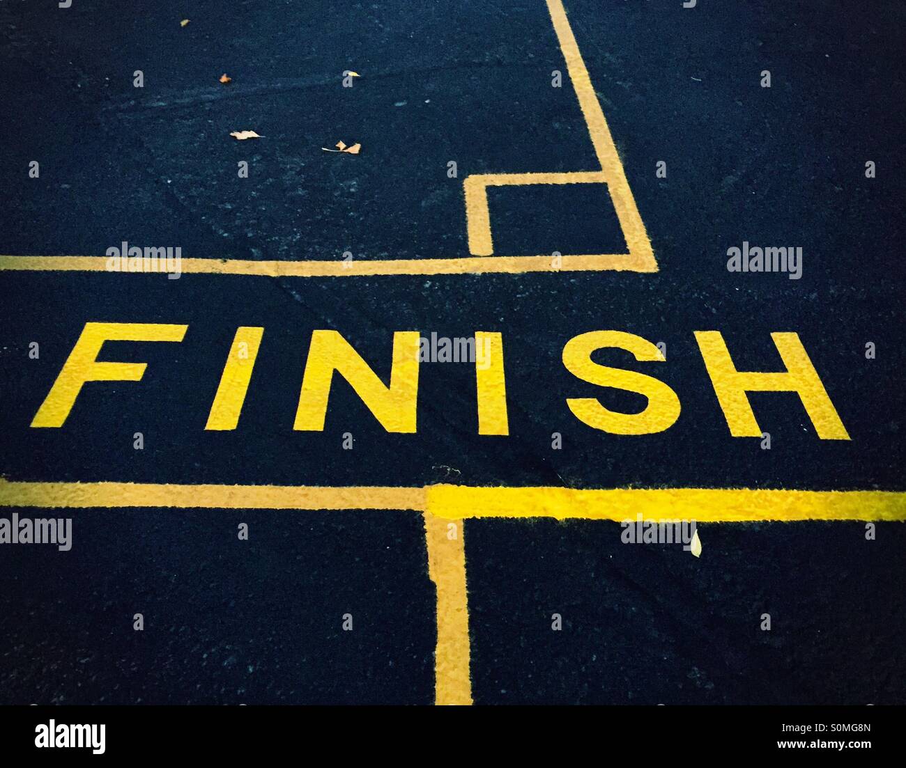 La parola 'Finish' dipinte in giallo su asfalto scuro. Foto Stock