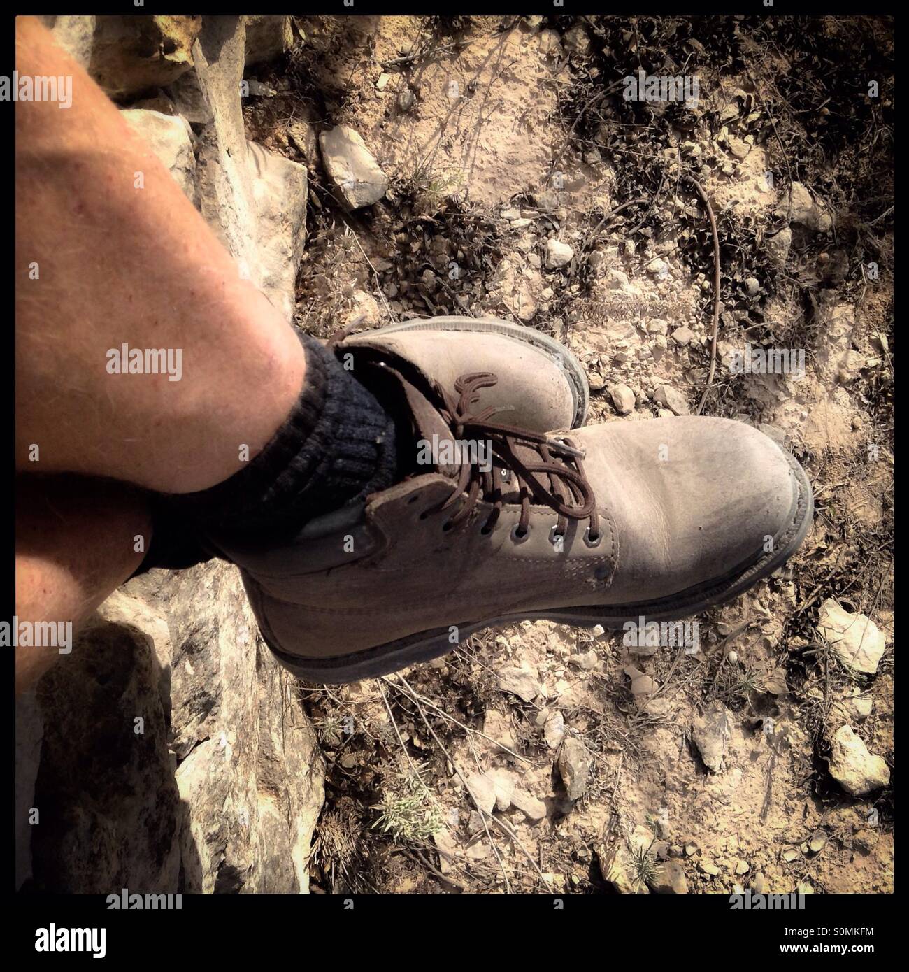 "Prendendo un riposo durante una escursione...' Uomo i piedi indossando scarponi circondato da montagne di pietrisco, Spagna. - Immagine stock catturata con smartphone