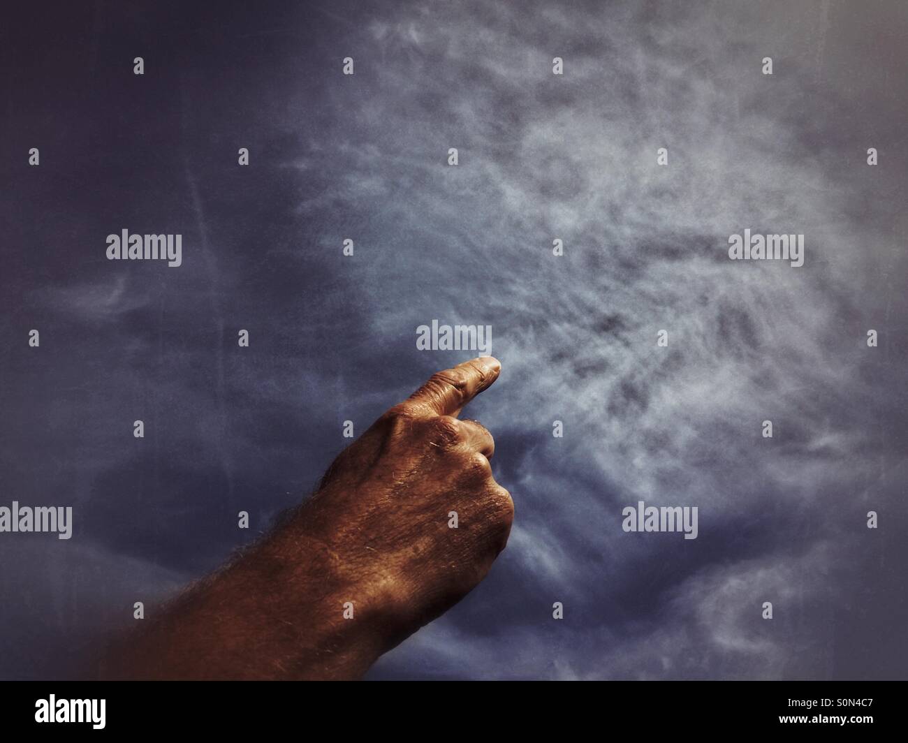 Mano d'uomo sembra disegnare le nuvole con un dito. Foto Stock