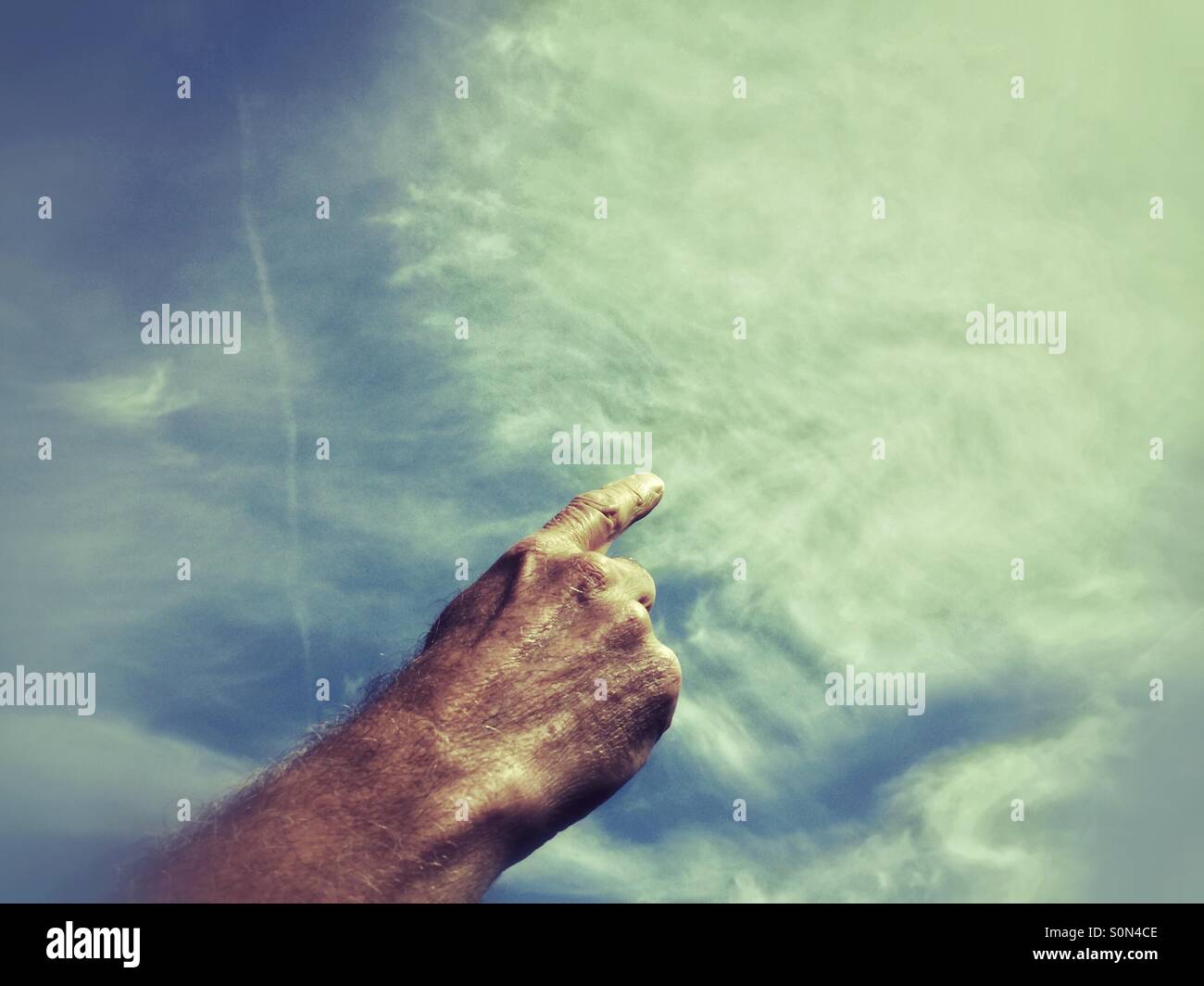 L'uomo la mano con il dito puntato sembra disegnare le nuvole nel cielo. - Immagine stock catturata con smartphone