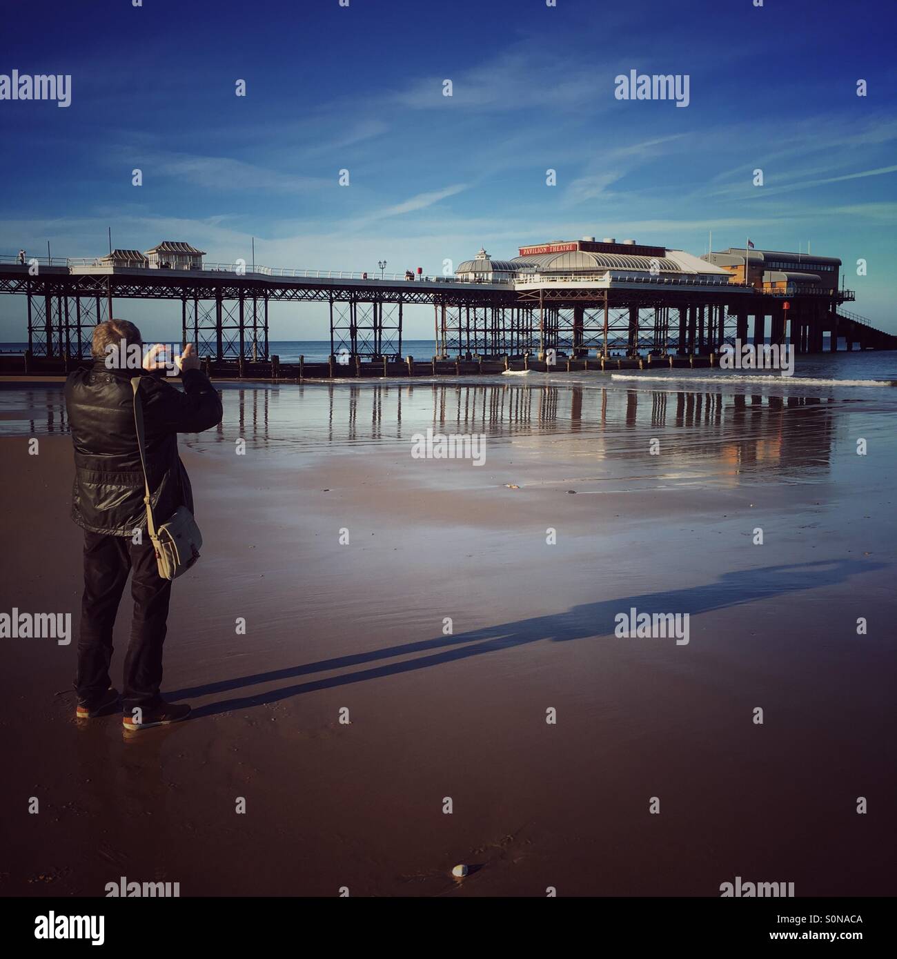 Un gentiluomo di scattare una foto del Cromer Pier in Norfolk Foto Stock