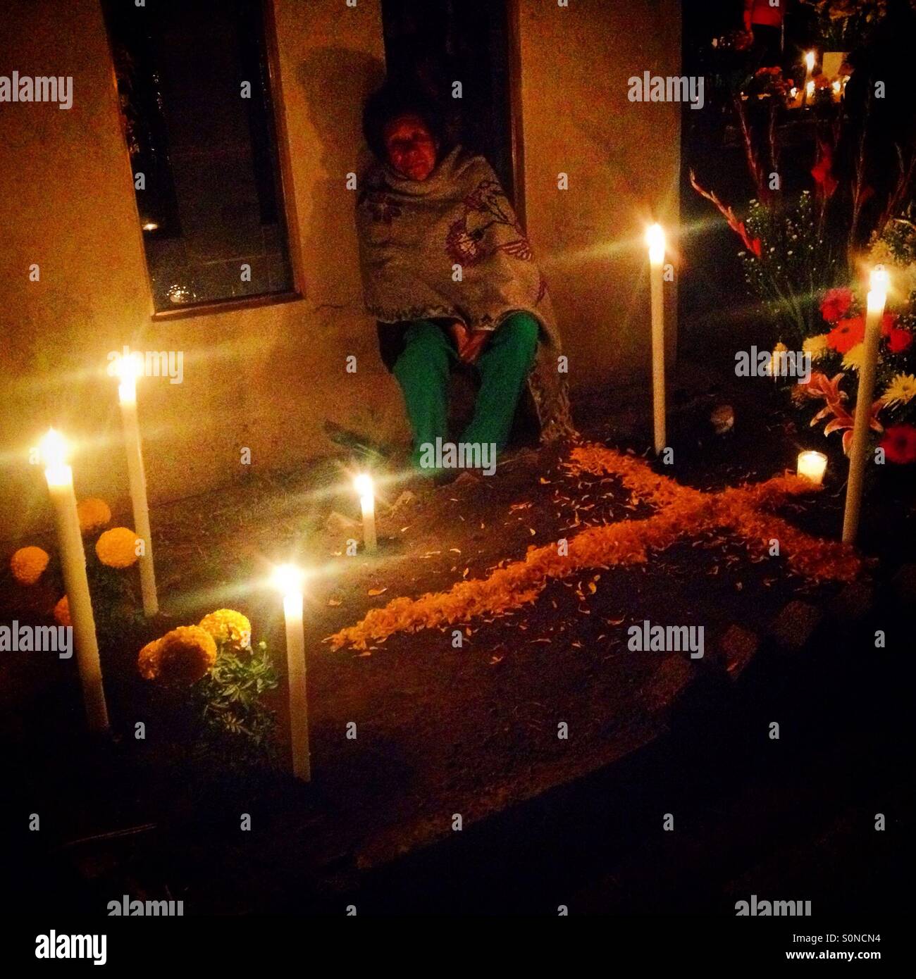 Una donna si siede con la sua tomba di famiglia durante il giorno dei morti celebrazioni in San Gregorio Atlapulco, Xochimilco, Città del Messico, Messico - Immagine stock catturata con smartphone