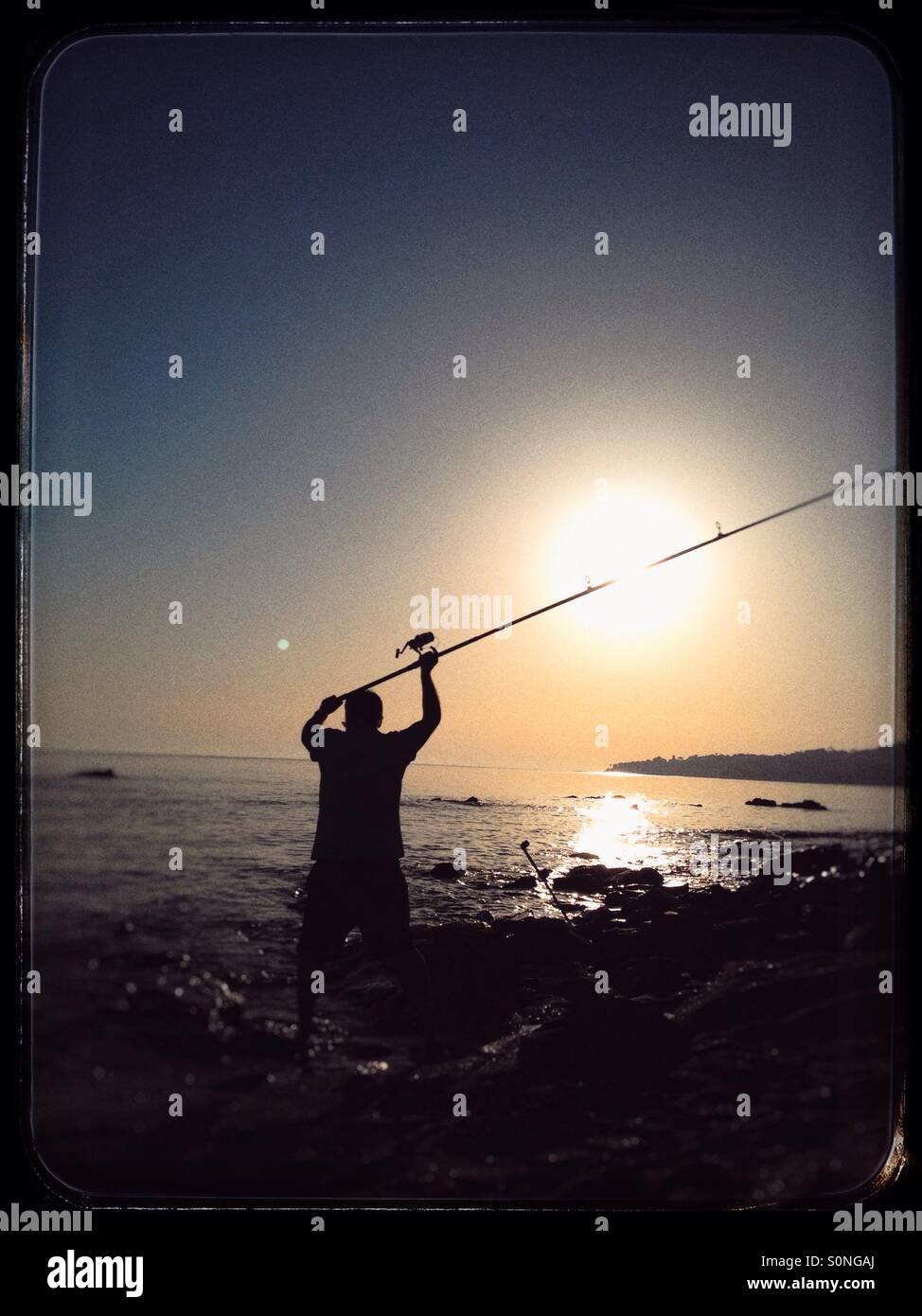 L'uomo la pesca al tramonto Foto Stock