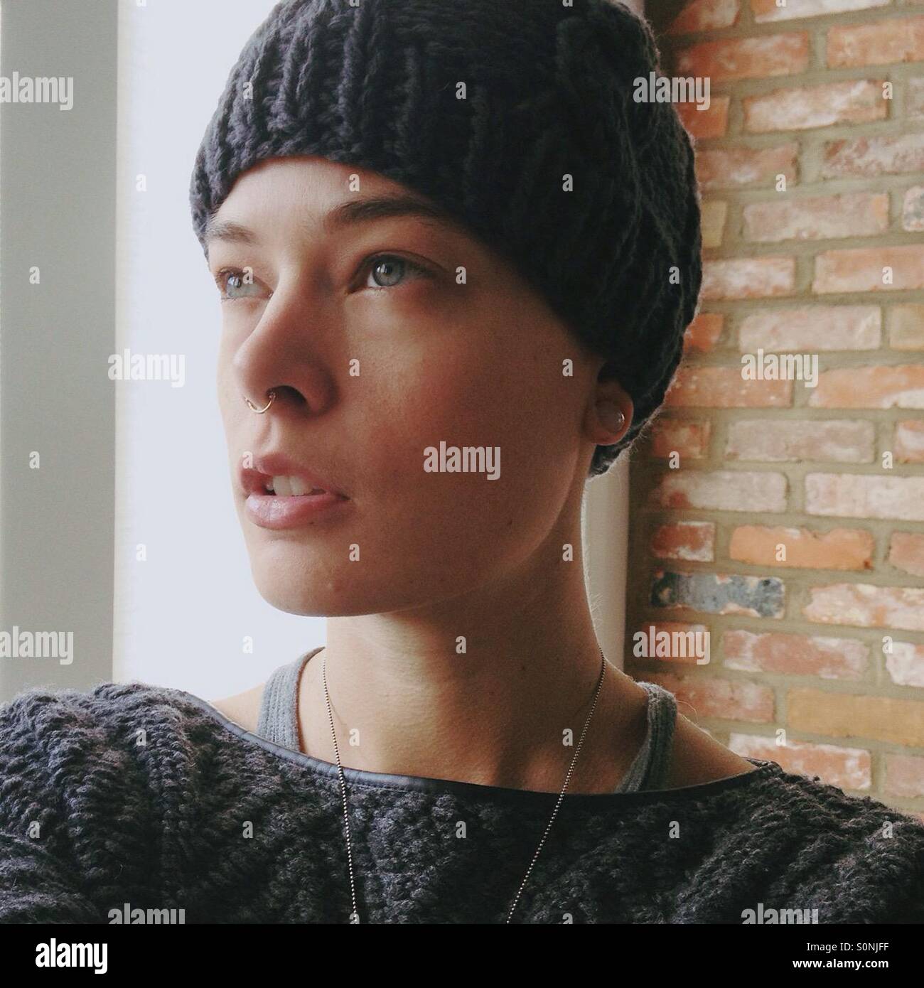 Ragazza con piercing in knit hat con soffusa illuminazione naturale Foto Stock