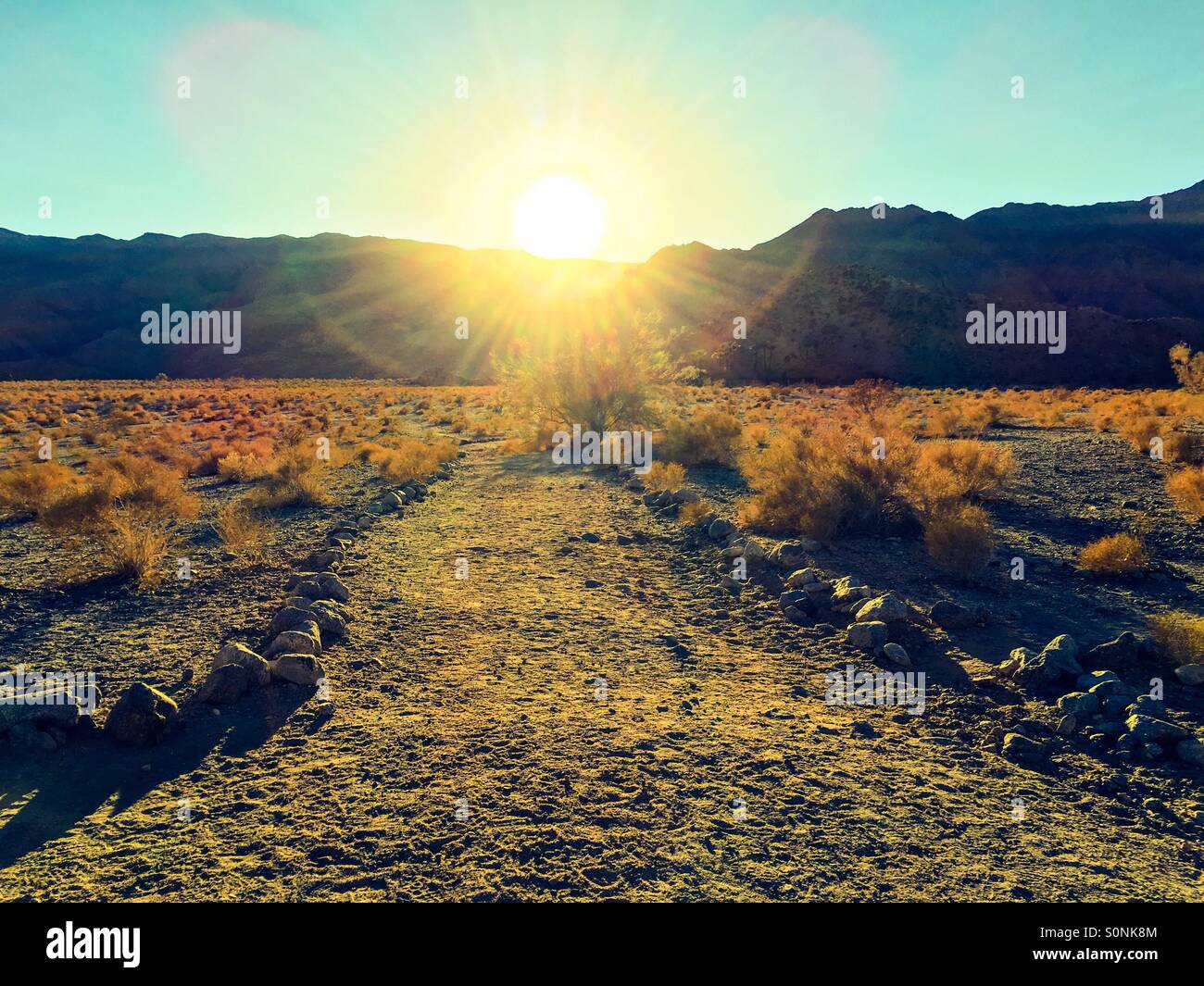 Il sole tramonta dietro le montagne Santa Rosa dietro La Quinta, California Foto Stock