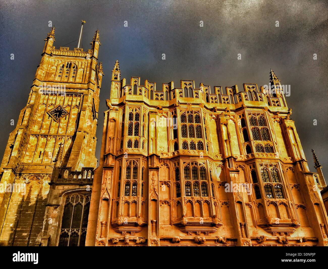 La Chiesa Parrocchiale di San Giovanni Battista, Cirencester Gloucestershire, Inghilterra. La torre quattrocentesca e grande portico sud sono inondate di mattina presto la luce del sole. Credito foto - © COLIN HOSKINS. - Immagine stock catturata con smartphone