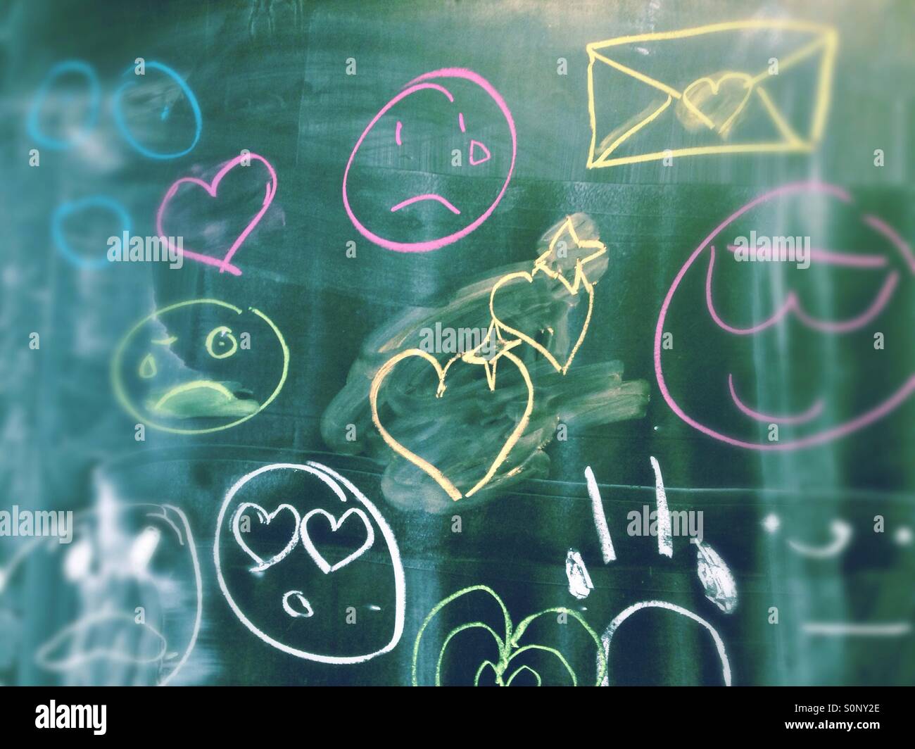 Emojis analogico ed emoticon scritto su una lavagna a scuola con gesso in diversi colori Foto Stock