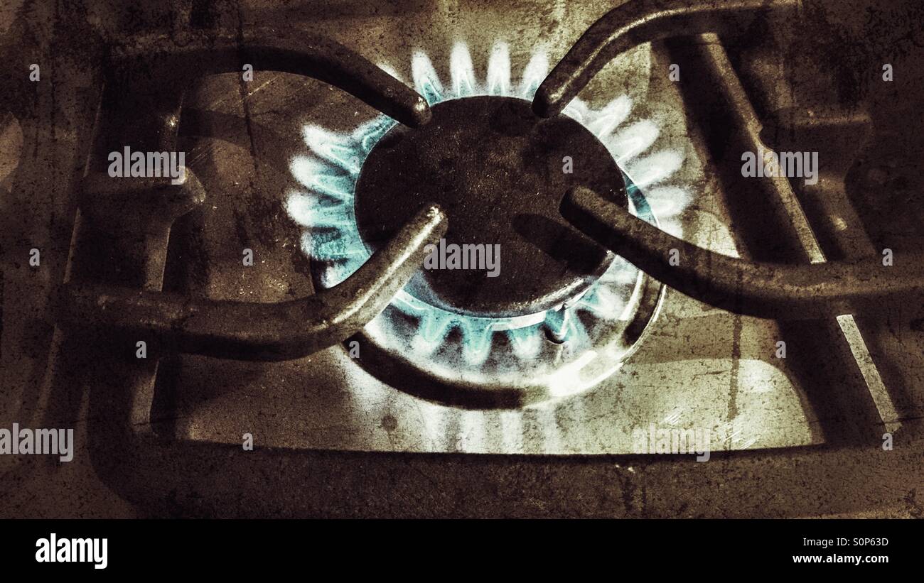 Accesa fornelli a gas ring bruciare con una fiamma blu, con un vintage, aspetto granuloso Foto Stock