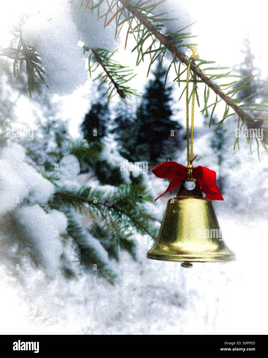 Campana d'oro appeso su un ramo di evergreen nella coperta di neve foresta. Vignette applicato. Foto Stock
