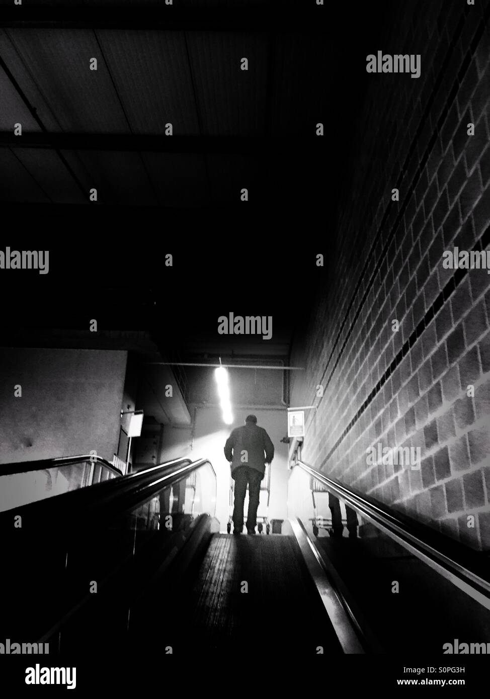 Un uomo su un elevatore meccanico con un carrello di shopping andando verso l'ingresso di un supermercato - Immagine stock catturata con smartphone
