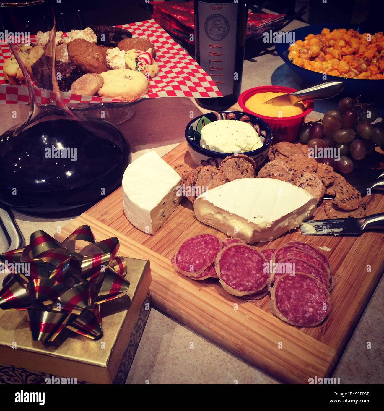 Vino rosso in caraffa e assortimento di formaggi e carni sul tagliere di legno con un regalo di Natale e cottura di Natale Foto Stock