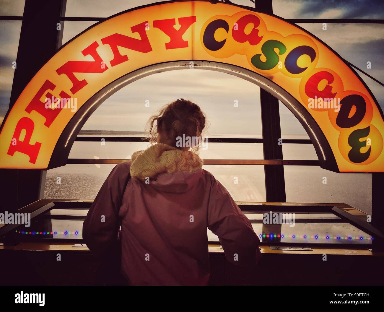 Ragazza giovane giocando in penny arcade Foto Stock