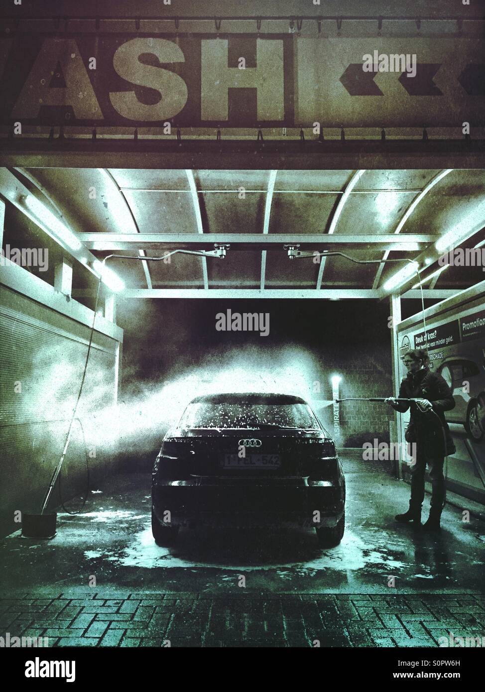 Pulizia della donna la sua auto in un self service car wash durante la serata - Immagine stock catturata con smartphone