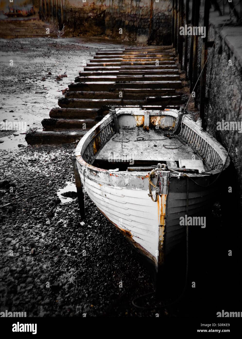 Piccola barca in attesa che la marea nel porto di Brixham Foto Stock